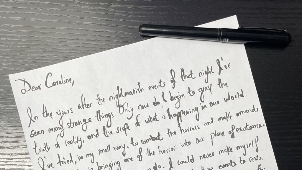 A letter in a script-style writing on white paper, and a black pen